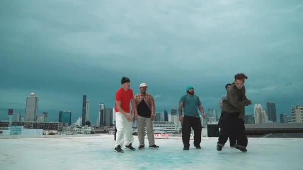 Professionelle Hipster in Freeze-Pose beim Schritt zur Musik auf dem Dach mit Blick auf die Stadt. Breakdancer führen Streetdance auf, umgeben von einer Hip-Hop-Tanzgruppe. Outdoor-Sport 2024. hiphop. - Filmmaterial, Video