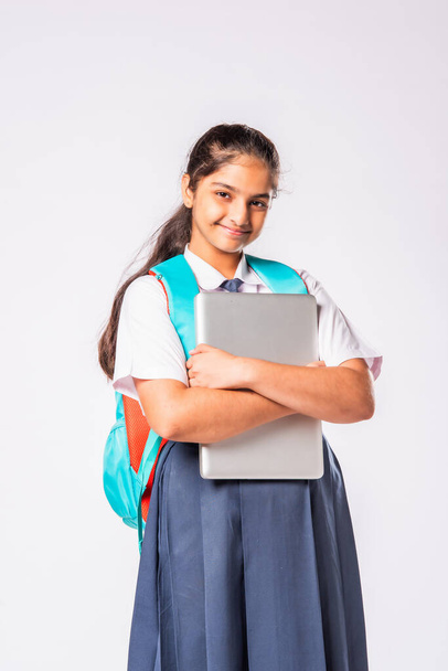 Indický asijské školačka v uniformě držení notebook proti bílému pozadí - Fotografie, Obrázek