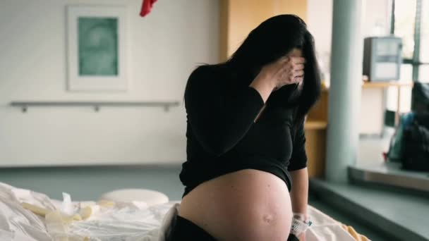 Drámai jelenet terhes nőkről, akiknek fájdalmaik vannak a szülés előtti összehúzódások során a kórházi klinikán, a beteg eltakarja a gyermekszüléssel küszködő arcot - Felvétel, videó