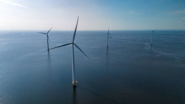 Un grupo de aerogeneradores se mantiene alto, flotando con gracia en el océano, aprovechando el poder del viento para generar energía limpia. - Foto, Imagen