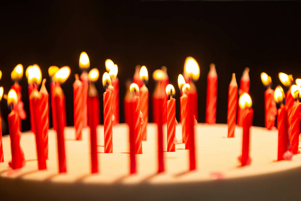 Detail mehrerer brennender Kerzen auf einer Geburtstagstorte. - Foto, Bild