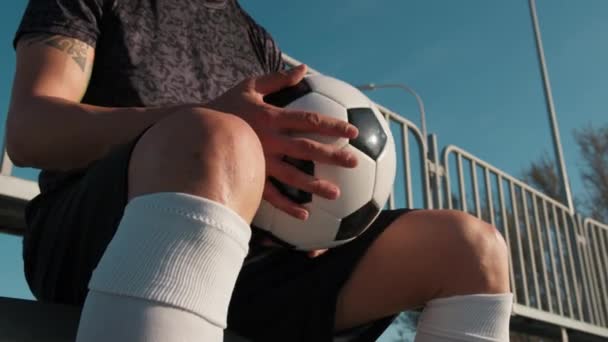 Footballeur fait des jeux avec balle dans la main assis dans le stand. - Séquence, vidéo
