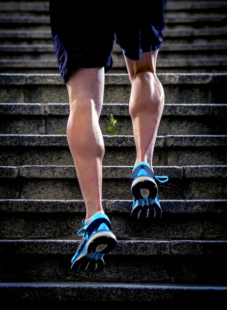 junge athletische Beine mit scharfen Schalmuskeln des Läufers Sportmann, der die Stadttreppe hinaufsteigt Joggen und Laufen im urbanen Training - Foto, Bild