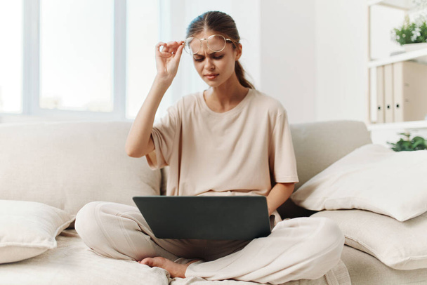 Connected Comfort: Een glimlachende vrouw die typt op een laptop in een gezellige woonkamer - Foto, afbeelding