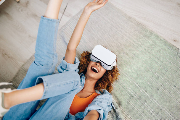 Mujer sonriente disfrutando del juego de realidad virtual en casa con gafas VR futuristas - Foto, imagen