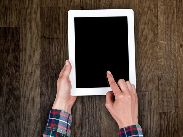 woman's hand holding a tablet on the background of a wooden tabletop - Foto, immagini