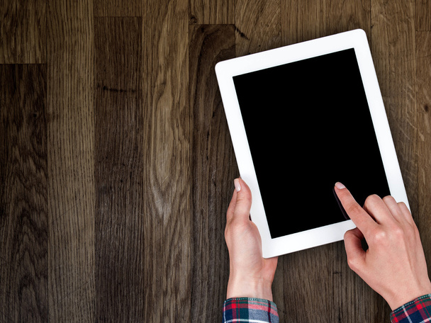 woman's hand holding a tablet on the background of a wooden tabletop - Photo, Image