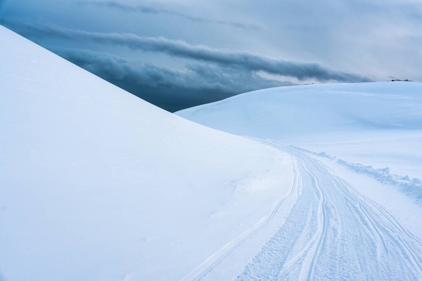 Белая ледниковая гора с заснеженными и снегоходными тропами на вершине зимой в Исландии - Фото, изображение