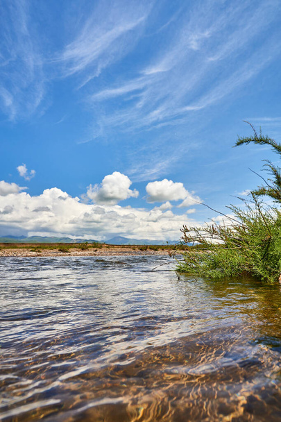 Пейзаж речной долины, гор и кучевых облаков над ними. Долина реки Шалкодесу в Казахстане - Фото, изображение