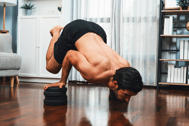 Athletic body and active sporty man lifting himself for effective targeting muscle bodybuilding gain at gaiety home as concept of healthy fit body home workout. Bodybuilder at home gym lifestyle. - Photo, Image