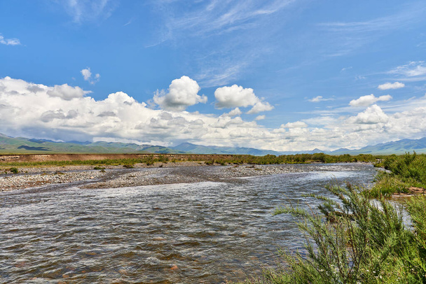 Tájkép a folyó völgyében, hegyek és kumulus felhők felettük. a Shalkodesu folyó völgye Kazahsztánban - Fotó, kép