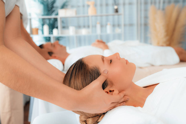 Caucasian couple enjoying relaxing anti-stress head massage and pampering facial beauty skin recreation leisure in dayspa modern light ambient at luxury resort or hotel spa salon. Quiescent - Photo, Image
