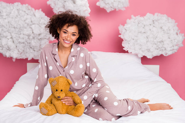 Photo of adorable positive lady wear pajama relaxing bed holding teddy bear isolated pink color background. - Photo, image