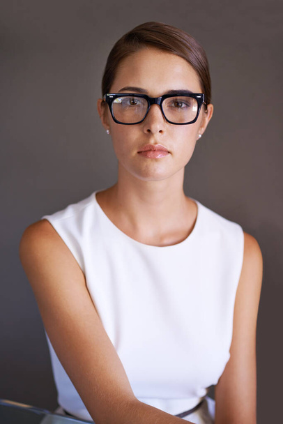 Mujer, seria y retrato en gafas con montura en estudio y gafas de moda para optometría. Consultor, confiado o cara para el trabajo en gafas, visión o mirada de prescripción por fondo marrón. - Foto, imagen