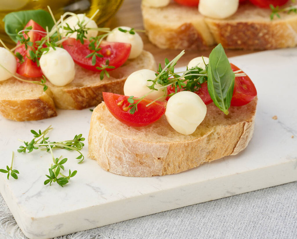 Круглый моцарелла, помидоры черри и микрозелень на куске белого хлеба, закрыть - Фото, изображение