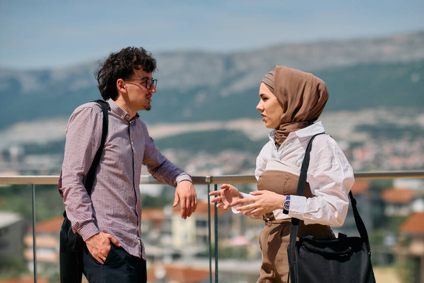 After a day at the office, a business man engages in conversation with his Muslim colleague wearing a hijab.  - Photo, Image