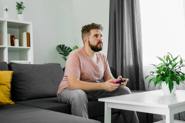 Man playing videogames in living room sitting on sofa - Photo, Image