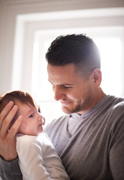 Father, baby and bonding with happiness and pride, growth and child development with love at family home. Man, infant or newborn with smile and dad holding kid for comfort, childhood and parenting. - Photo, Image