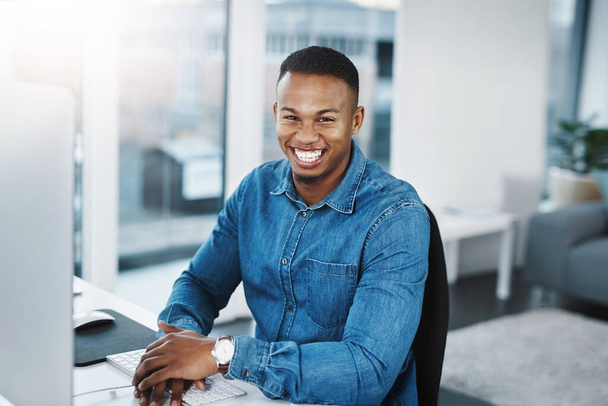Portrait, smile and black man by computer in office, workspace and desk happy in creative career. Happiness, internship and journalist with technology for typing, research and internet for working. - Photo, Image