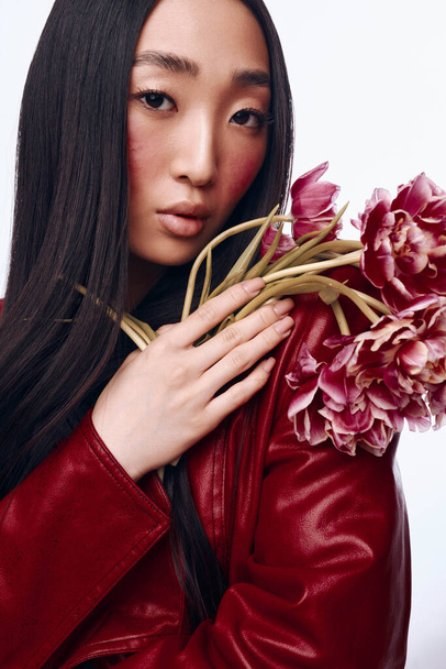 Nainen tyylikäs punainen nahkatakki tilalla kukkakimppu edessä kasvot, seisoo ulkona - Valokuva, kuva