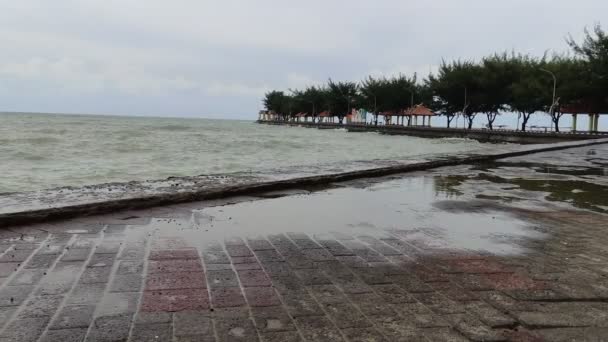 olas grandes en un lugar turístico junto a la playa que está a punto de llover - Metraje, vídeo