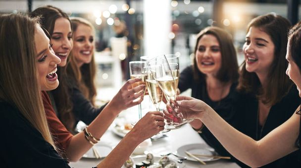 Group, women and champagne for toast in restaurant for dinner party, celebration and sushi with lens flare. Friends, cheers and happy by table with alcohol glass, girls night and seafood for congrats. - Photo, Image