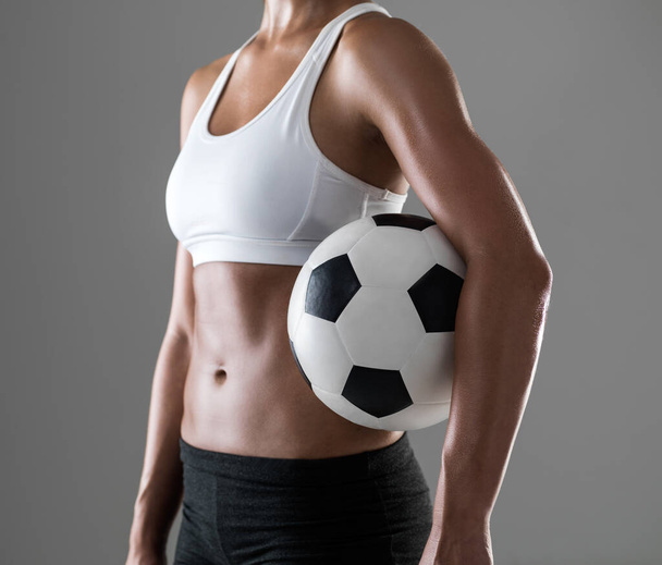 Woman, closeup and soccer player with ball for match, game or fitness on a gray studio background. Body of female person or athlete with football for sports exercise, workout or training on mockup. - Photo, Image