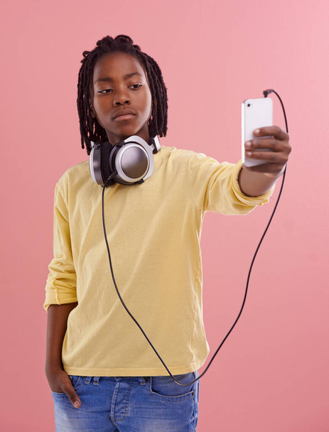 Teen, boy and selfie of student in studio with headphones for listening to music and post on social media. High school, kid and live streaming on blog with pride and confidence in profile picture. - Photo, Image
