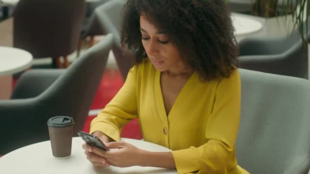 Mujer afroamericana infeliz en la cafetería con la cabeza de teléfono inteligente notificación de teléfono móvil SMS mensaje de error pérdida molesto problema femenino dificultades desglose estresado chica triste problemas cansados - Imágenes, Vídeo
