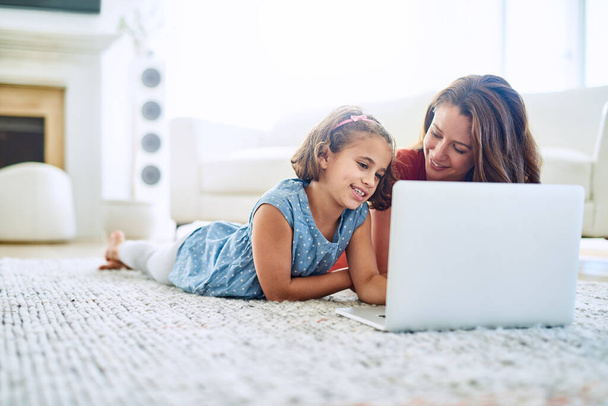 Mother, girl and laptop for learning in home, online class and remote homeschool or education on floor. Daughter, mama and streaming cartoon or app for development, bonding and support in childhood. - Photo, Image