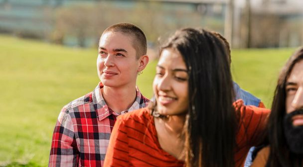 Close-up of young friends sharing a moment of joy and camaraderie in a sunny urban park, embodying youth and diversity. - Photo, Image