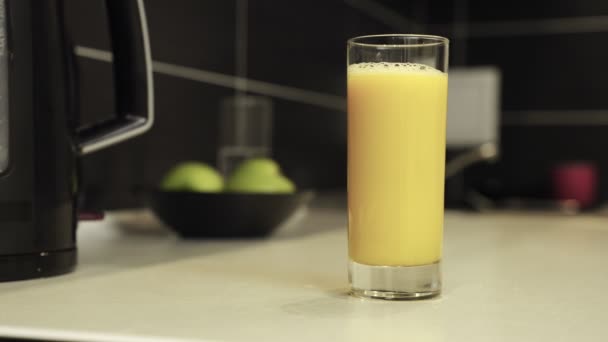 Ręka mężczyzny trzymająca szklankę soku pomarańczowego w kuchni w domu. Zamknij drzwi. Koncepcja zdrowego odżywiania, diety i napojów. Zwolniony ruch - Materiał filmowy, wideo