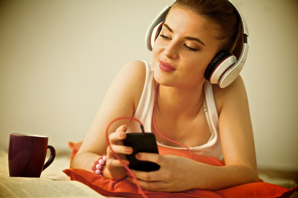 Young woman lying on floor and listen to music - Foto, Bild