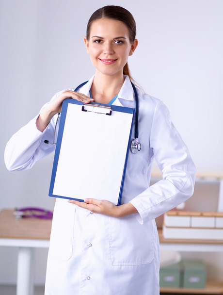 Smiling female doctor with a folder in uniform standing - Фото, зображення