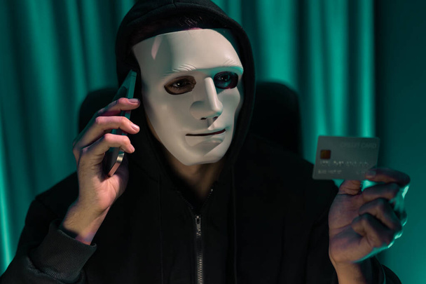White criminal anonymous mask calling to credit card owner to threaten ransom with privacy information all database, making password encryption by programming hack trying to make insecure. Pecuniary. - Photo, Image