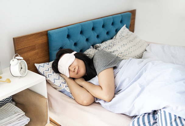 Visão superior Jovem asiática usa pijama e máscara de olho deitado na cama dormir passar tempo no quarto lounge casa no próprio quarto hotel acordar sonho. Conceito imobiliário.  - Foto, Imagem