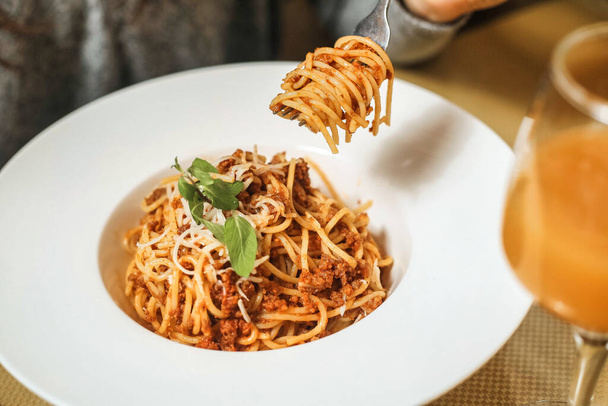 Um garfo levanta um prato de espaguete, mostrando o delicioso e tradicional prato italiano. - Foto, Imagem