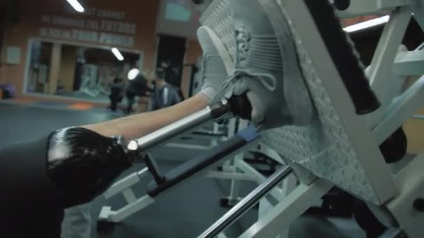 Sledování záběru motivovaného sportovce s protetickým tréninkem na stroji na lisování nohou v moderní tělocvičně. Dospělý sportovní muž s umělou končetinou dělá sílu cvičení pomocí profesionálního sportovního vybavení. - Záběry, video