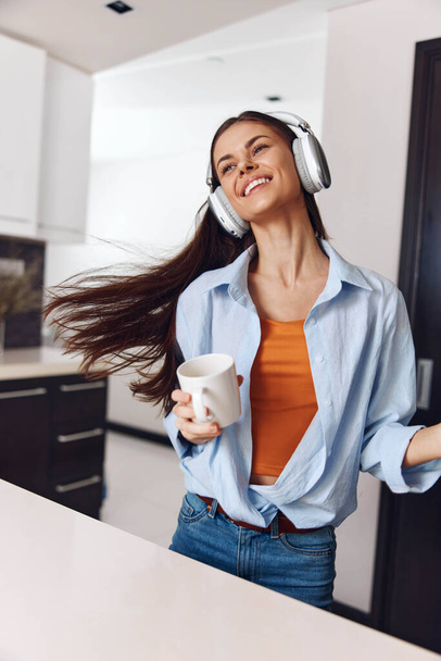 Frau genießt Musik und Kaffee einen entspannten Moment mit Kopfhörern und einer Tasse Heißgetränk zu Hause - Foto, Bild