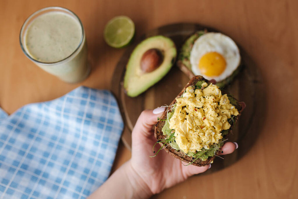 Вид сверху на тост из авокадо с яйцом. Здоровый и вкусный завтрак. Зеленый смузи. Высокое качество фото - Фото, изображение
