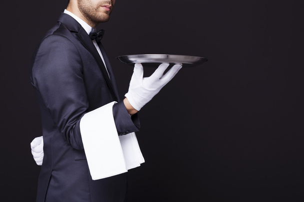 Waiter holding an empty silver tray - Foto, afbeelding
