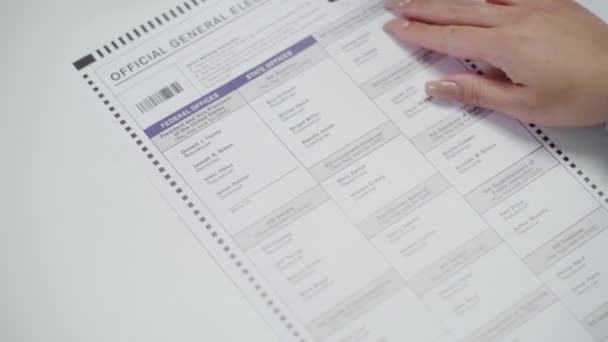 ZAPORIZHYA, UCRANIA - 15 DE MARZO DE 2024: Acercamiento de la ciudadana anónima estadounidense llenando papeleta en la cabina de votación. La mujer vota por Donald Trump en el colegio electoral. Día Nacional de Elecciones en el - Imágenes, Vídeo