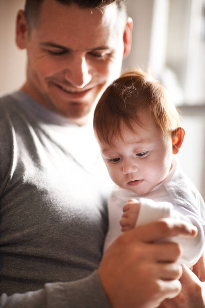 Ευτυχισμένος, η αγάπη ή ο πατέρας και το μωρό σε ένα σπίτι με φροντίδα, εμπιστοσύνη και την ανάπτυξη του παιδιού, υποστήριξη ή συγκόλληση. Οικογένεια, ασφάλεια και μπαμπάς με παιδί στο σπίτι για μάθηση, ασφάλεια ή πρωινά παιχνίδια με ευγνωμοσύνη. - Φωτογραφία, εικόνα