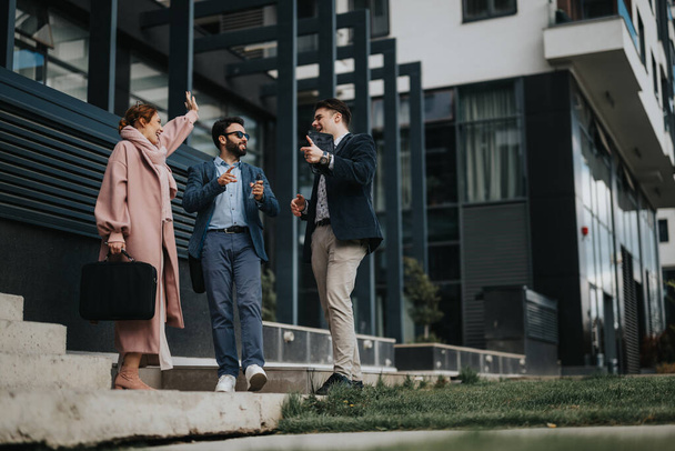 Tres jóvenes emprendedores participan en una discusión estratégica al aire libre, con la mujer haciendo gestos mientras sostiene un archivo y dos hombres escuchando atentamente. - Foto, Imagen