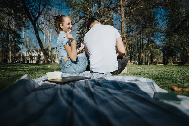 Due studenti delle scuole superiori siedono sull'erba in un parco, circondati da libri e quaderni, che studiano insieme all'aperto. - Foto, immagini