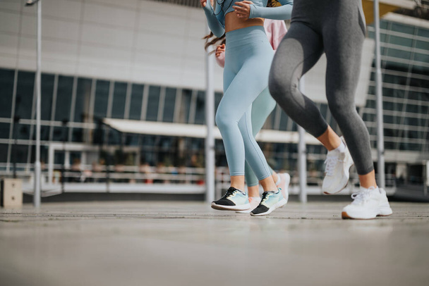 Atletik giyinen iki kadın, aktif bir yaşam tarzını vurgulayarak bir şehir ortamında koşu seansına katılıyorlar.. - Fotoğraf, Görsel