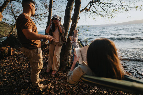 Группа друзей разбивает лагерь у живописного озера, окруженного природой, олицетворяя дух приключений и единения. - Фото, изображение