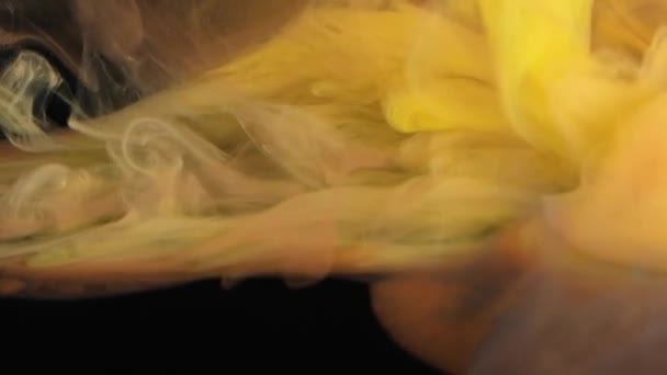 Een close-up weergave van de delicate werveling van rook boven een bed van levendige oranje en gele texturen. - Video