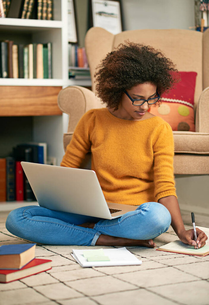Laptop, books and African woman in library, floor and writing notes for education. Study, learning and female student with natural afro hair, assignment or technology for knowledge and reading. - Photo, Image