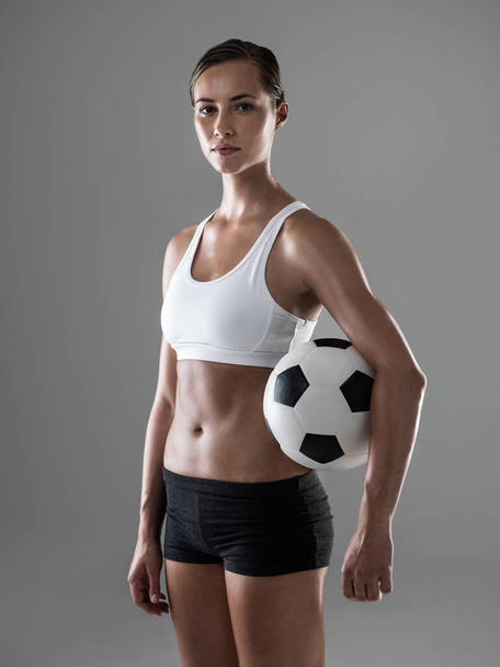 Woman, portrait and soccer player with ball for match, game or kick off on a gray studio background. Female person or athlete with football for sports exercise, workout or training on mockup space. - Photo, Image